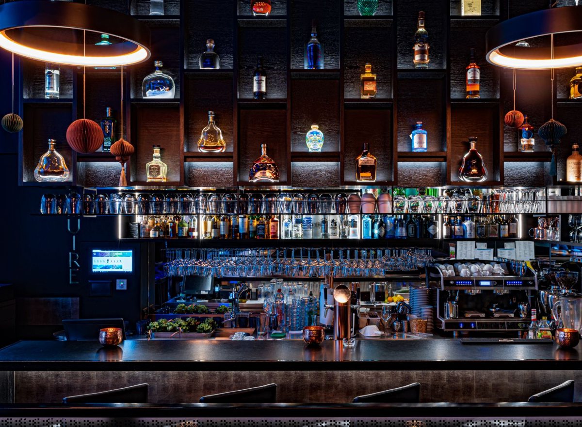 Die Bar im Esquire – beleuchtete Flaschenwand und Kupfer-Ringleuchten